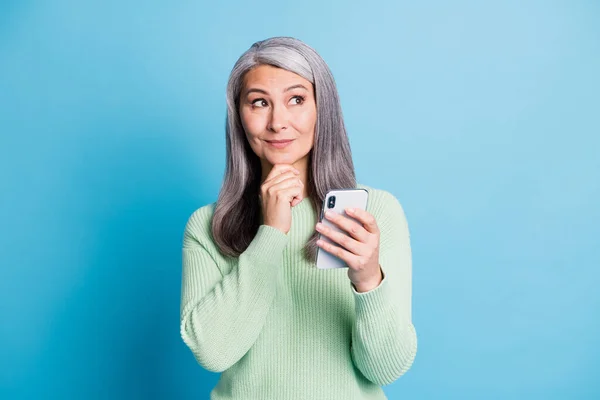 Meraklı yaşlı bir kadının fotoğrafı. Telefona dokun. Yüzüne yeşil kazak geçir. — Stok fotoğraf