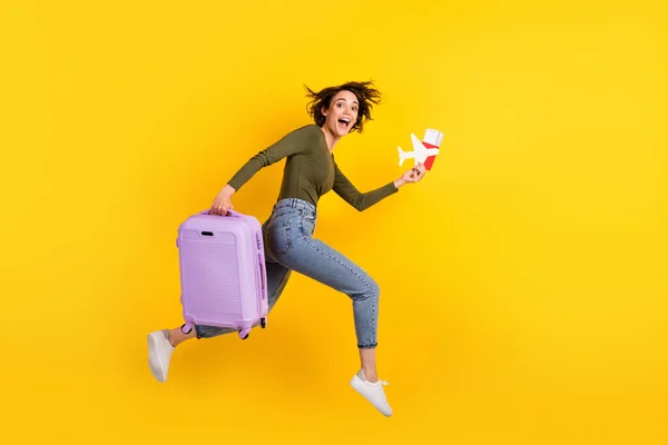 Foto lateral de perfil de tamanho completo de salto menina louca correr rápido com o visto de avião de bagagem isolado no fundo de cor amarela brilho — Fotografia de Stock