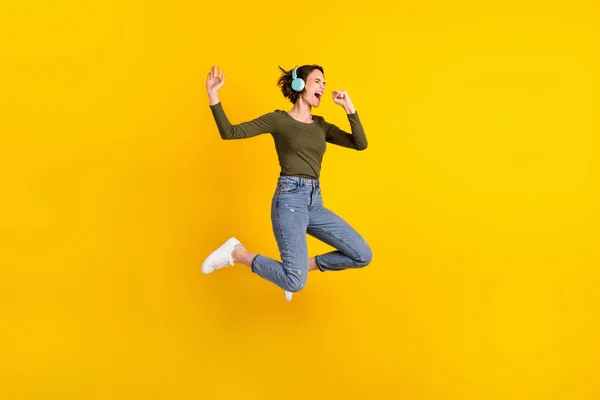 Full body photo of girl jump listen music on wireless headset sing song use hand as mic isolated over shine color background — Stock Photo, Image