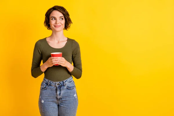Foto de encantadora menina segurar xícara de café olhar espaço vazio isolado sobre vibrante cor amarela fundo — Fotografia de Stock