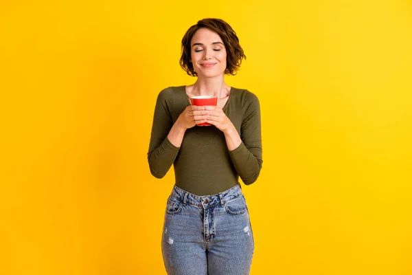Bild av charmig flicka lukt aromatiskt kaffe i kopp isolerad över ljust gul färg bakgrund — Stockfoto
