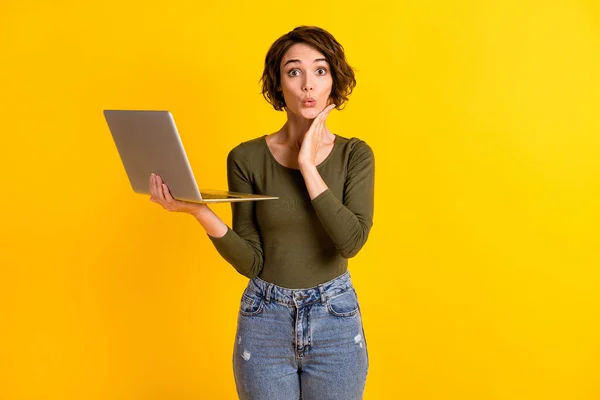 Foto av förvånad dam hålla laptop touch ansikte med handen isolerad över levande gul färg bakgrund — Stockfoto