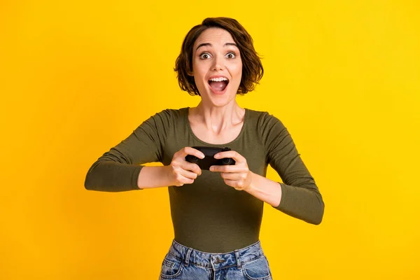 Foto van positieve vrolijke meisje spelen video game met joystick slijtage jumper geïsoleerd over levendige gele kleur achtergrond — Stockfoto