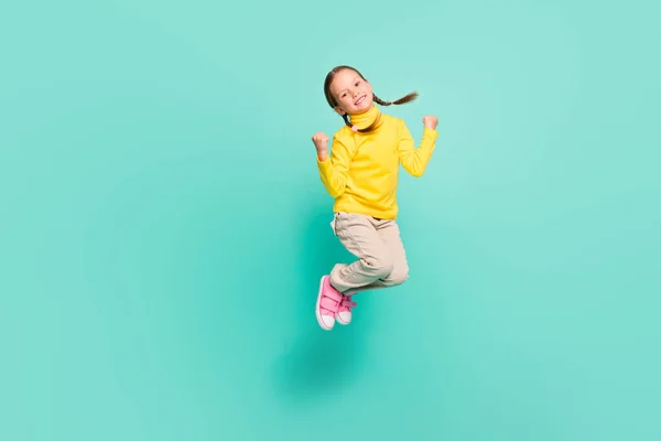 Ganzkörper-Foto von braunen Haaren glücklich Mädchen springen Luft Glück Verkauf heben Fäuste tragen gelben Pullover weiße Hose isoliert auf Krickente Farbe Hintergrund — Stockfoto