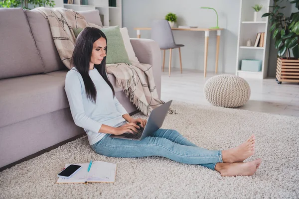 Plná velikost fotografie seriózní žena práce z domova použití notebook psaní sedět podlaha uvnitř domu — Stock fotografie