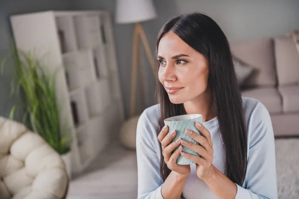 Foto de la hermosa mujer de ensueño mantenga la taza de té mirar lejos inspirado buenos días en la sala de estar casa interior —  Fotos de Stock