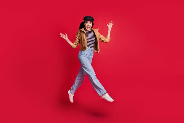 Full size foto van aantrekkelijke dame springen verhogen armen open mond ongelooflijk aanbod geïsoleerd op rode kleur achtergrond — Stockfoto