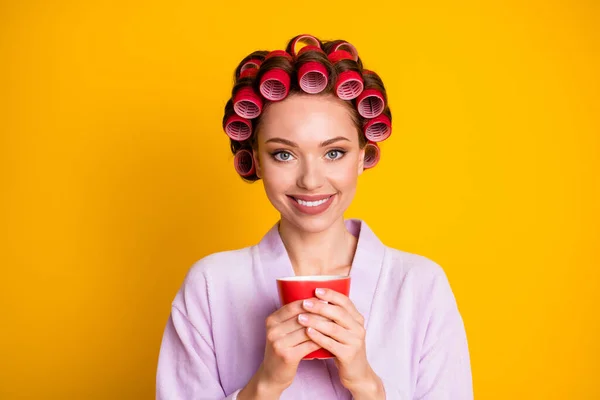 Gros plan portrait de charmante femme gaie portant des bigoudis boire boisson chaude isolé sur fond de couleur jaune vif — Photo