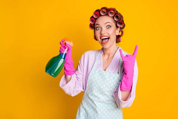 Crazy meisje gebruik chemische spray fles tonen gehoornde symbool dragen badjas handschoenen geïsoleerde gele kleur achtergrond — Stockfoto
