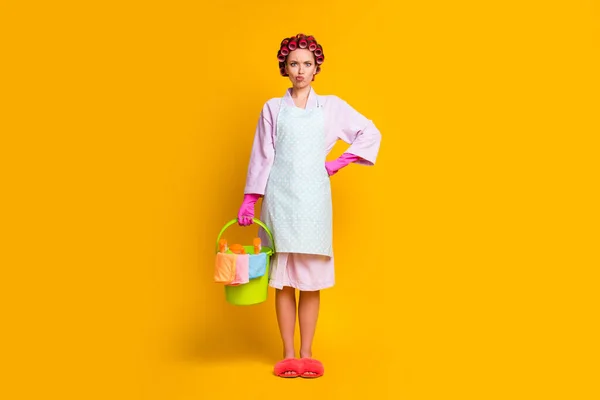 In voller Länge Foto enttäuscht Mädchen halten Eimer Sprühflasche tragen Handschuhe Bademantel isoliert Glanz Farbe Hintergrund — Stockfoto