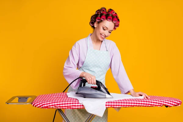 Portret van glamoureuze gericht vrolijk meisje strijken kleding geïsoleerd over helder oranje kleur achtergrond — Stockfoto