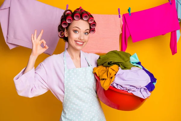 Retrato de atractiva dama alegre glamorosa llevando colgando cosas lavadas mostrando ok-signo aislado color naranja brillante fondo — Foto de Stock