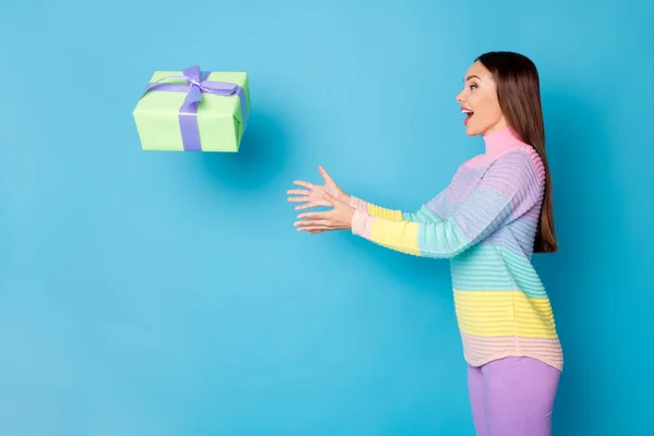 Foto samping profil gadis heran mendapatkan hadiah kotak terbang menangkap udara mengenakan celana panjang sweater terisolasi biru latar belakang warna — Stok Foto