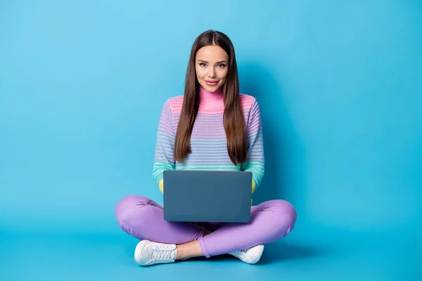 Retrato de linda chica alegre sentado posición de loto piernas cruzadas utilizando búsqueda web portátil aislado en fondo de color azul brillante — Foto de Stock