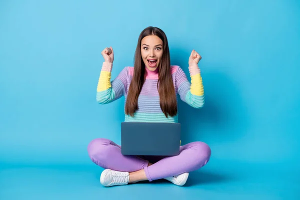 Retrato de chica alegre bastante alegre sentado posición de loto cruzó las piernas con el ordenador portátil que se divierte aislado sobre fondo de color azul brillante — Foto de Stock