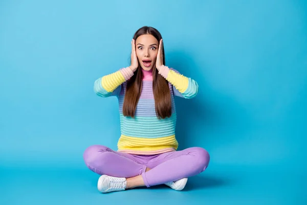 Retrato de chica alegre asombrada sentada posición de loto piernas cruzadas buena noticia reacción aislado color azul brillante fondo —  Fotos de Stock