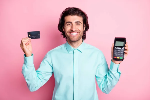 Foto retrato de cara segurando cartão de crédito e terminal em mãos isoladas no fundo de cor rosa pastel — Fotografia de Stock