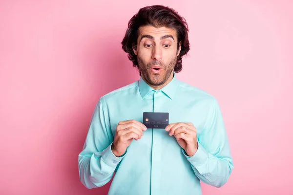 Photo portrait of surprised man holding debit card in two hands isolated on pastel pink colored background — Stock Photo, Image