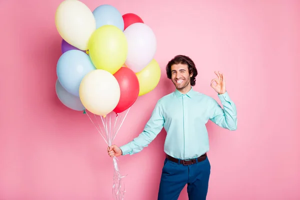 Φωτογραφία πορτρέτο του κλείνοντας το μάτι του ανθρώπου δείχνει ok-σημάδι κρατώντας μπαλόνια ηλίου που απομονώνονται σε παστέλ ροζ φόντο — Φωτογραφία Αρχείου