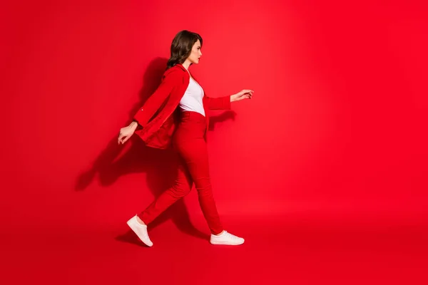 Teljes méretű profil oldalán fotó szép csinos lány séta üres tér elszigetelt felett élénk piros színű háttér — Stock Fotó