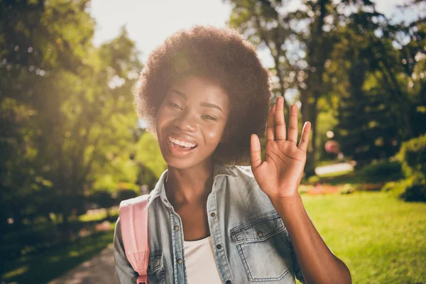 Foto porträtt av glad afrikansk amerikansk flicka viftande hand bär denim jacka i solsken i naturen — Stockfoto