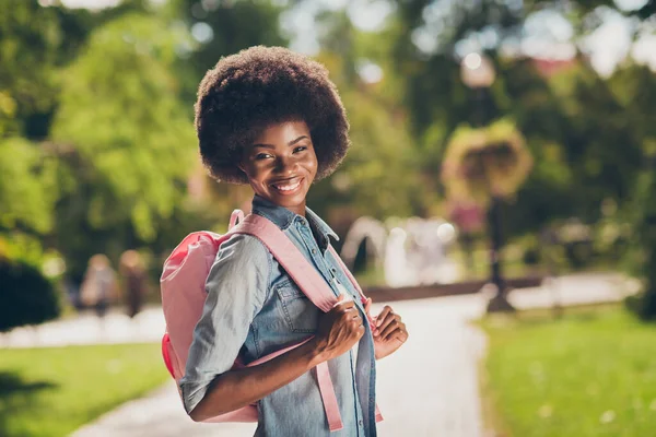 Zijprofiel foto van zwart gevild mooi meisje met krullend haar lachend vrolijk houden tas op rug dragen stijlvolle casual denim shirt — Stockfoto