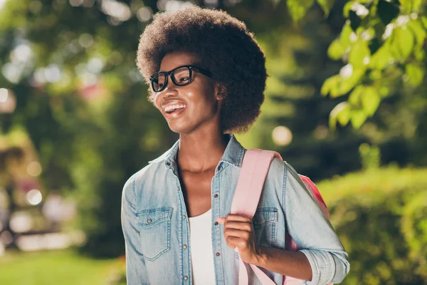 Zdjęcie portret dość ładny czarny skóry kręcone dziewczyna śmiejąc się radośnie noszenie modne okulary dżinsy koszula plecak — Zdjęcie stockowe