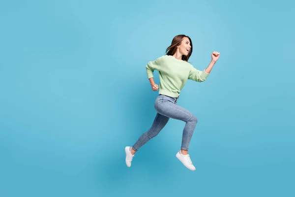 Plná délka tělo velikost boční profil fotografie hezké mladé dívky běží vpřed rychlé skákání s úsměvem izolované na pulzující modré barvy pozadí — Stock fotografie