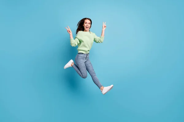 Lunghezza intera dimensione del corpo profilo laterale foto di bella giovane studentessa dimostrando gesto v-segno con entrambe le mani saltando sorridente isolato su vibrante sfondo di colore blu — Foto Stock