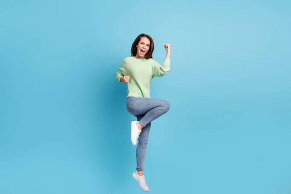 Tamanho do corpo de comprimento total foto de funky jumping up menina vestindo roupas casuais gritando alto como um vencedor sorrindo isolado no fundo de cor azul brilhante — Fotografia de Stock