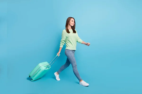 Foto retrato de chica bonita satisfecha que va a viajar manteniendo la maleta apresurándose sonriendo aislada sobre un fondo de color azul vivo —  Fotos de Stock