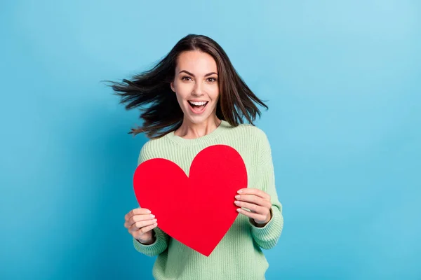 Foto retrato de menina morena estudante segurando vermelho coração símbolo de amor rindo em movimento sorrindo isolado no fundo de cor azul vívido — Fotografia de Stock