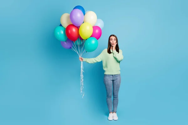 밝은 청색 배경에 특유의 의상을 입고 헬륨 풍선을 들고 있는 놀란 소녀의 전체 몸길이 사진 — 스톡 사진