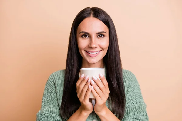 Potret gadis optimis memegang cangkir mengenakan sweater hijau terisolasi di latar belakang warna persik — Stok Foto