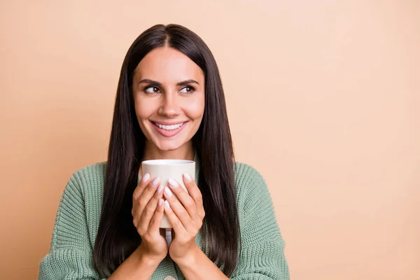 Retrato de chica optimista mantenga taza mirada espacio vacío desgaste suéter verde aislado sobre fondo de color melocotón — Foto de Stock