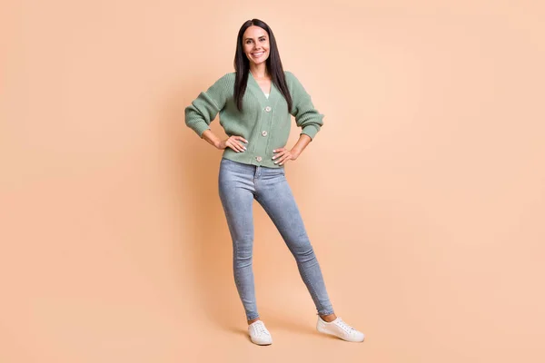 Piena lunghezza foto di positivo felice donna tenere le mani vita usura verde cardigan jeans isolato su sfondo di colore beige — Foto Stock