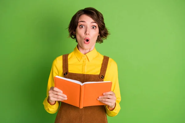 Foto von schockierten hübschen Mädchen halten Buch suchen Kamera offenen Mund tragen gelbes Hemd insgesamt isoliert grüne Farbe Hintergrund — Stockfoto