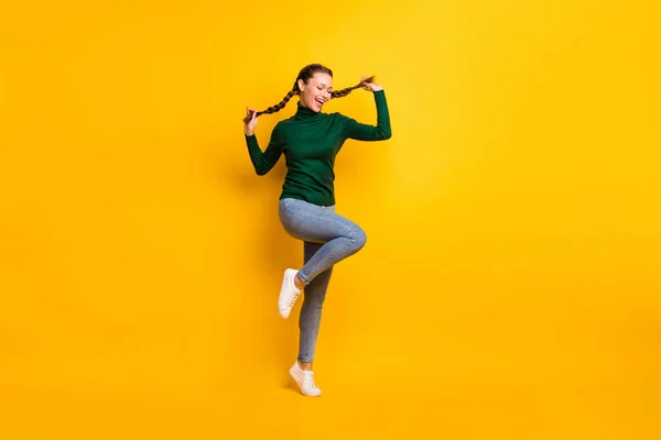Longitud completa cuerpo tamaño foto juguetón chica bailando tocando coletas aisladas en pastel amarillo color fondo —  Fotos de Stock
