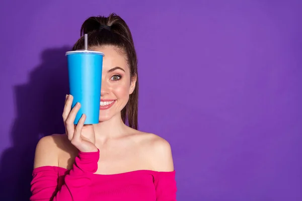 Photo of lady hold cup cover eye smiling empty space look camera wear pink unclothed shoulders top isolated purple color background — Stock Photo, Image