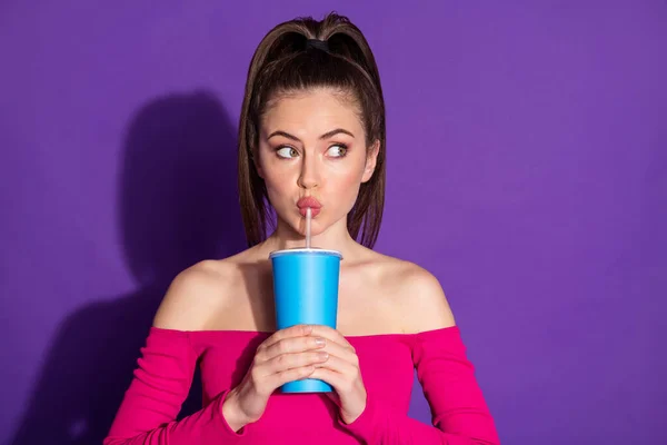 照片上的年轻女士拿着杯子吸管喝苏打水的样子空荡荡的空间思考问题穿着粉色上衣孤立的紫色背景 — 图库照片