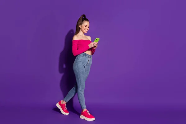 Full body size photo of lovely lady hold telephone blogging walk wear pink uncovered shoulders top isolated purple color background — Fotografia de Stock