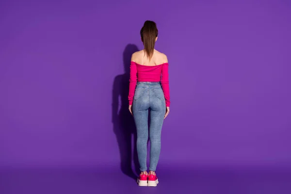 Полноразмерная задняя часть кузова, сзади вид привлекательной стройной девушки в smart casual, изолированной ярко-фиолетовым цветом фона — стоковое фото