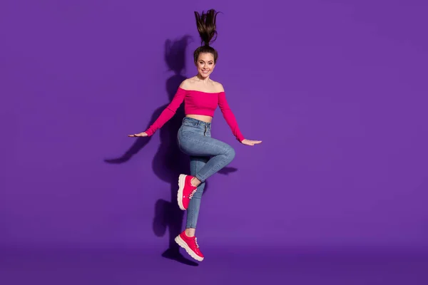 Повнометражний вигляд на тіло досить весела дівчина, яка весело стрибає позує ізольовано на яскраво фіолетовому кольоровому фоні — стокове фото