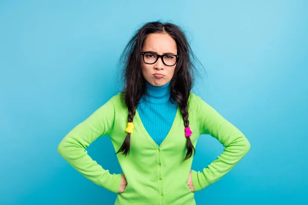 Foto van boos ongelukkig schattig jonge vrouw dragen groene shirt handen vuisten op taille slecht humeur geïsoleerd op blauwe kleur achtergrond — Stockfoto