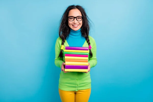 Photo de joyeuse jeune femme tiennent pile de livres portent chemise verte isolé sur fond de couleur bleue — Photo