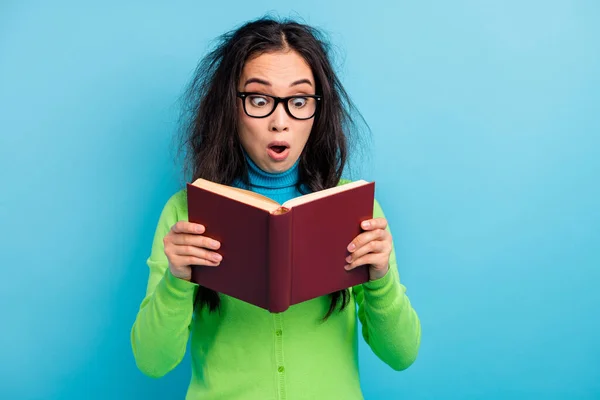 Foto von überrascht erstaunt junge Frau halten gelesenes Buch unglaublichen Roman isoliert auf glänzend blauem Hintergrund — Stockfoto