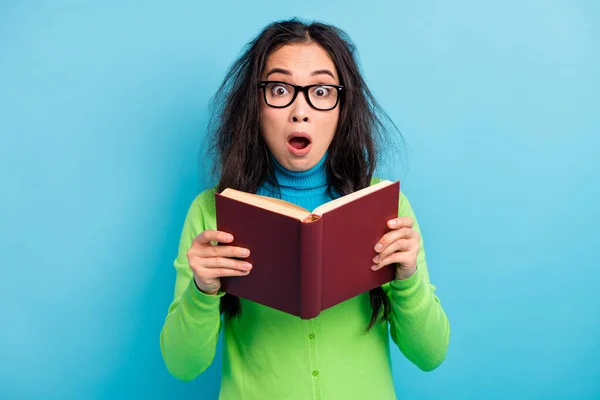 Photo de effrayé jeune femme tenir livre porter des lunettes de chemise verte isolé sur fond de couleur bleue — Photo