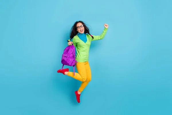 Foto em tamanho completo de alegre estudante segurar saco levantar punho desgaste camisa verde calças amarelas isoladas no fundo de cor azul — Fotografia de Stock