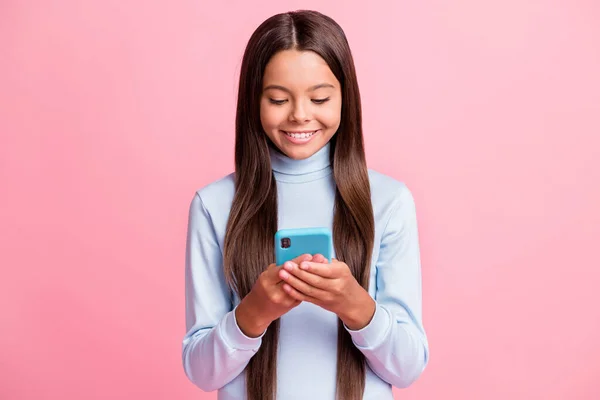 Close-up retrato de menina de cabelos castanhos muito alegre focado usando dispositivo gadget isolado sobre cor pastel rosa fundo — Fotografia de Stock