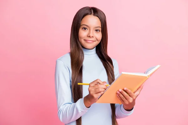 Retrato de conteúdo alegre atraente menina inteligente escrevendo notas copybook diário isolado sobre cor de fundo pastel rosa — Fotografia de Stock